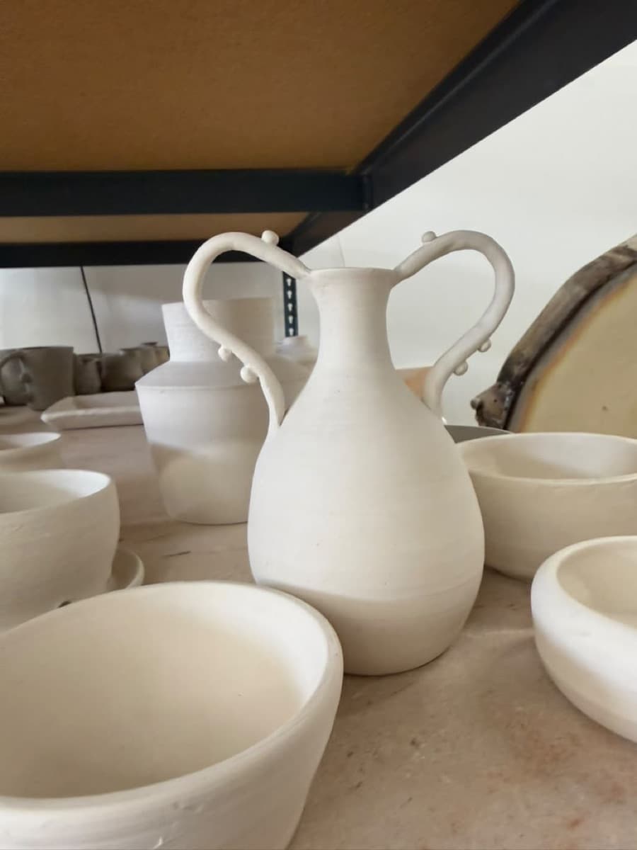 A two-handled bisque pitcher with beaded handles, made in the Colibri member studio