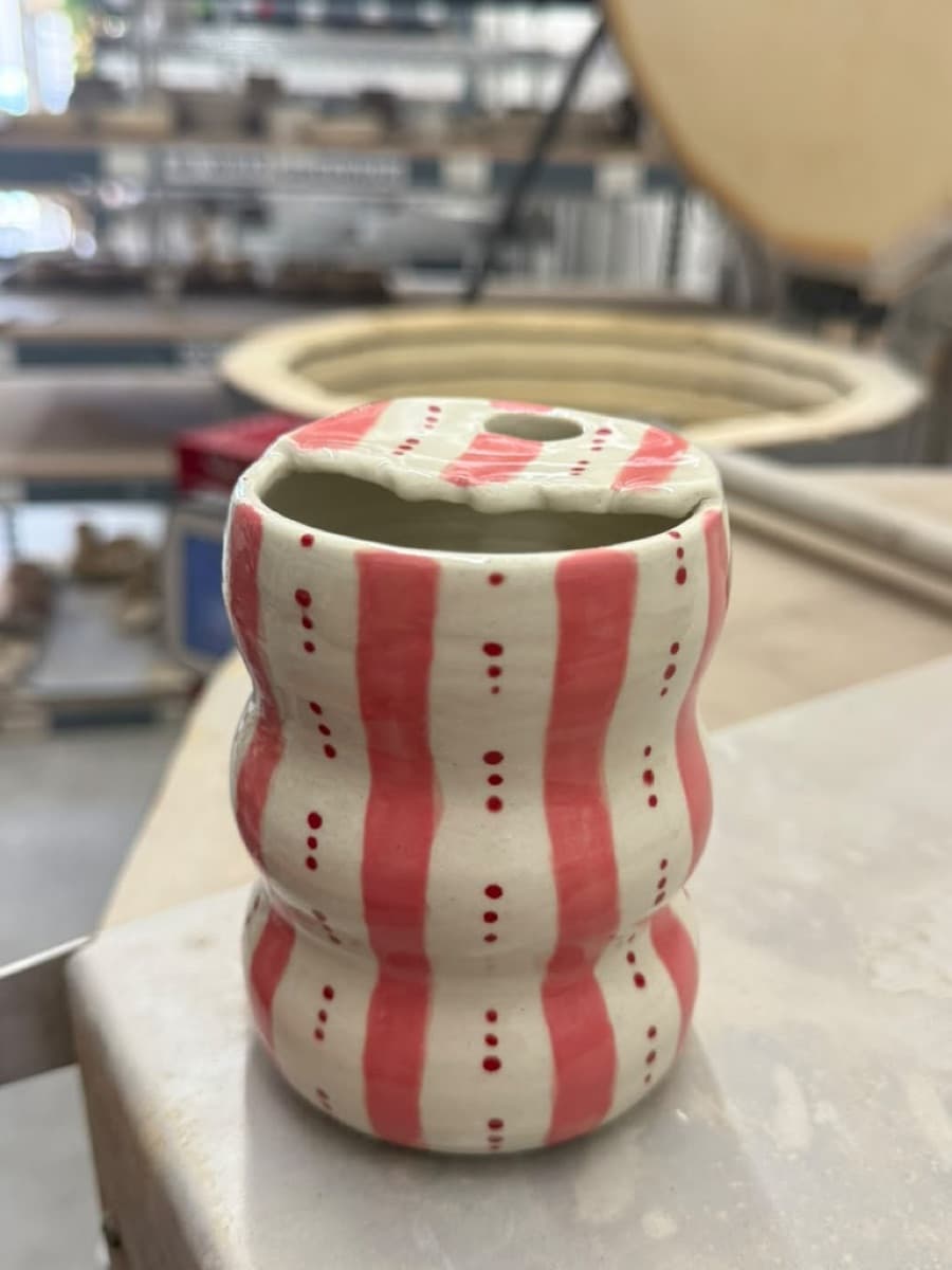 A finished cup with pink and red stripes and a soft wavy form